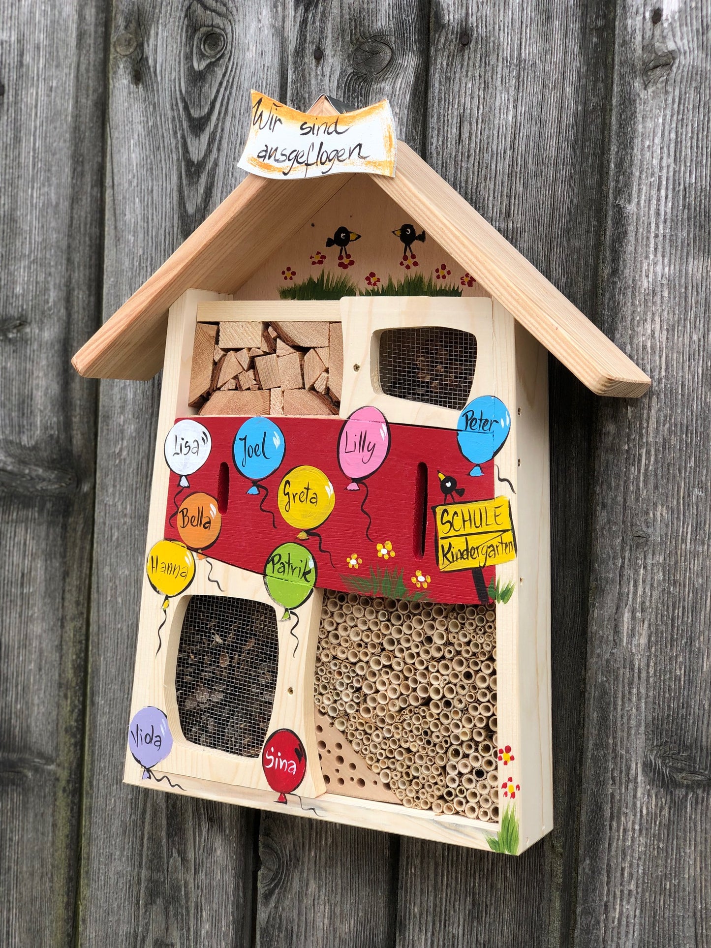 Cadeau d'adieu pour l'enseignante de maternelle : hôtel à insectes rouge avec les noms des enfants dans des ballons colorés